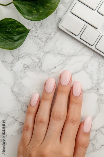 beautiful nail natural A hand with manicured nails rests on a marble surface near a keyboard and greenery.
