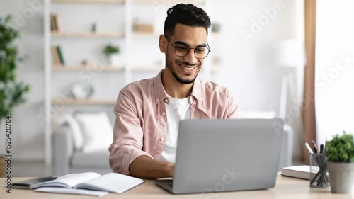 Cheerful Young Man with Laptop Working from Home with Positive Emotion