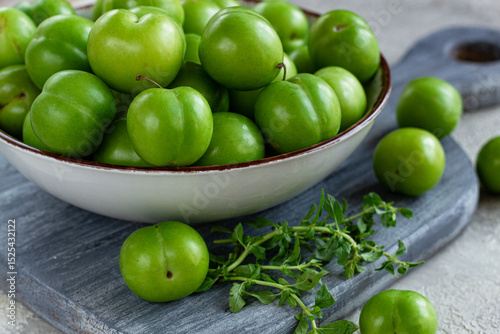 Tkemali, green cherry plum, in a bowl, on a gray table, top view, natural light, no people,