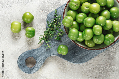 Tkemali, green cherry plum, in a bowl, on a gray table, top view, natural light, no people,