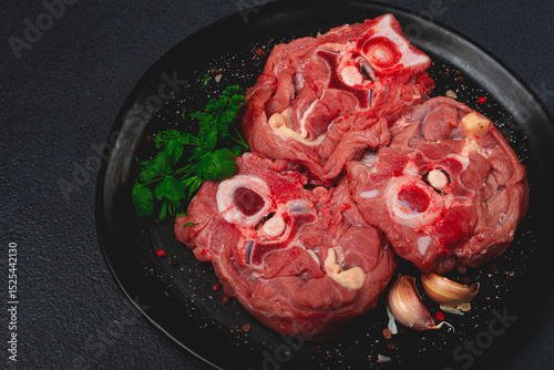 raw steak, calf's neck on the bone, fresh meat, on a black plate, top view, no people,