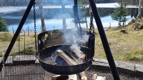 campfire with birch tree log smoke and lake background