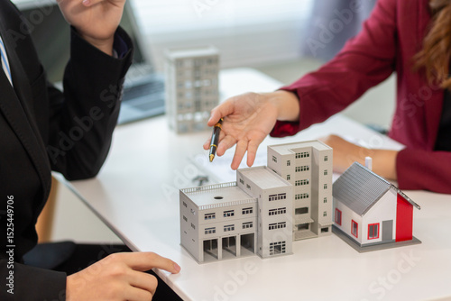 Inside a real estate office a real estate agent is presenting a condominium unit for sale to a client and offering a valuable promotion to entice the client to purchase their own property. copy space