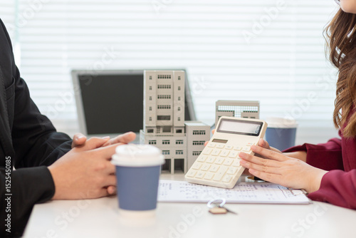 Inside a real estate office a real estate agent is presenting a condominium unit for sale to a client and offering a valuable promotion to entice the client to purchase their own property. copy space