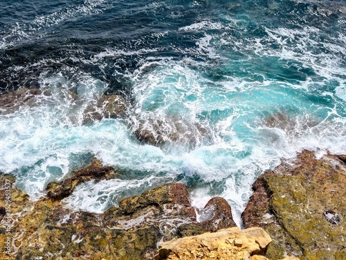 Waves Crashing on Rocky Shoreline – Aerial View of Turquoise Sea Foam and Coastal Texture