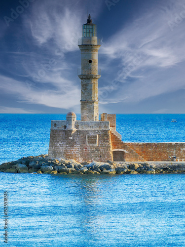 The Venetian Harbour Lighthouse stands tall on a sunny day, guiding ships into the picturesque harbor of Chania