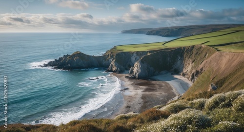 Coastline with cliffs, sandy beach, and green fields overlooking the ocean. Natural landscape, coastal scenery, and rural terrain.