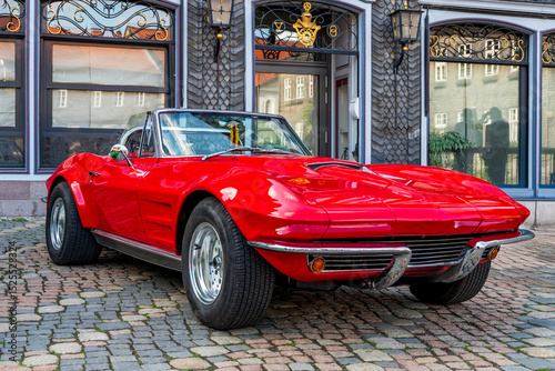 red classic american sportscar in front of historical building
