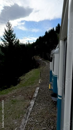 Train travels along scenic route through wilderness with green trees and cloudy sky on a serene day