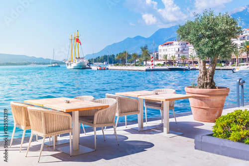 Tivat,Montenegro waterfront dining experience in Boka Bay with stunning Adriatic views and serene ambiance,featuring an inviting outdoor cafe restaurant,clear blue waters,majestic mountains and yachts