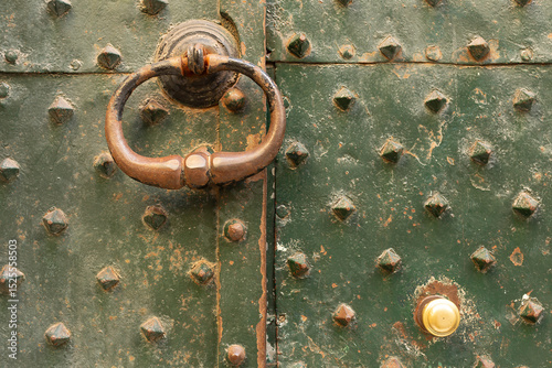 Ornate brass metal door knocker on a metal covered door, Genoa