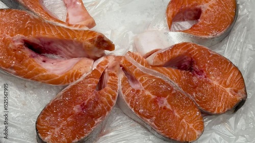 Steaks of chilled Atlantic salmon from frozen raw materials on a substrate with ice for sale in the supermarket. Close-up.