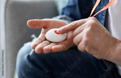 Closeup of man's hand pressing alarm button for emergency on his chest, home interior. Unrecognizable mature man pushing panic button on emergency equipment for elderly people, cropped photo