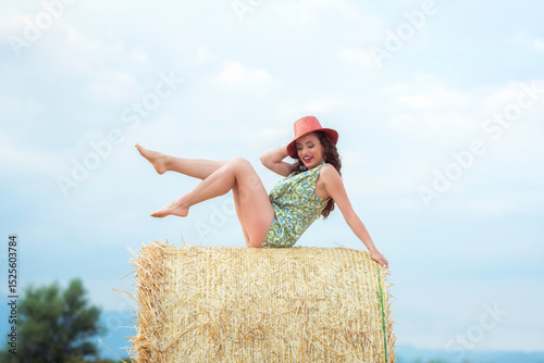 Woman sitting confidently on hay bale with intense gaze and natural sunlight