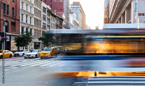 City bus driving through the busy intersection of 5th Avenue and 23rd Street in New York City with motion blur