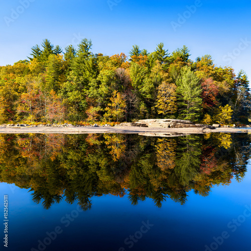 Colorful fall trees reflected in still water creates a mirrored landscape in a Pennsylvania mountain forest