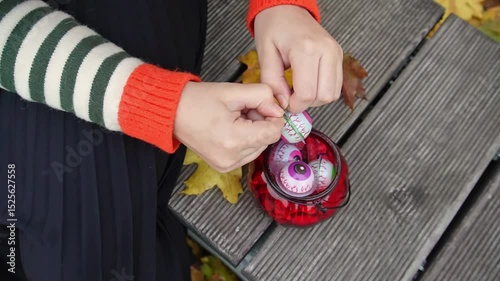 The girls hands open the plastic packaging on multicolored candy eyes
