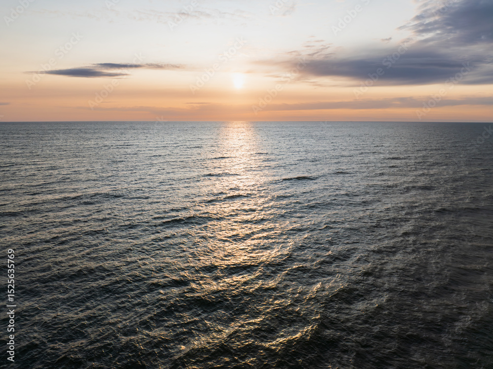 Obraz premium An aerial drone view of the serene Baltic Sea during the summer White Nights, with the low sun reflecting on the calm waves.