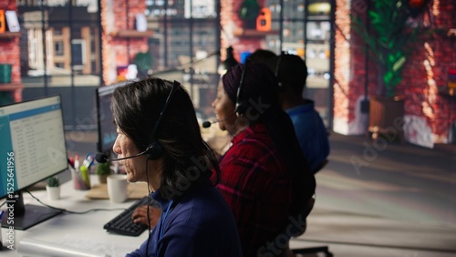 Experienced worker talking with customer using headphones mic to gain new sales. Asian account manager in office using audio headset, speaking with client to generate leads, camera B close up