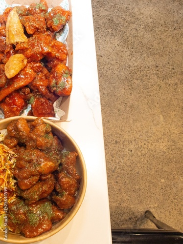 Korean deep dried spicy red chicken sauce in a paper takeaway box.