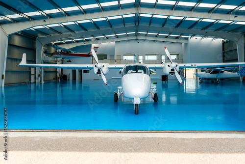 White twin engine airplane parked inside hangar