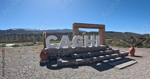 Cachi welcomes visitors with a stunning landscape and vibrant sign under a bright blue sky