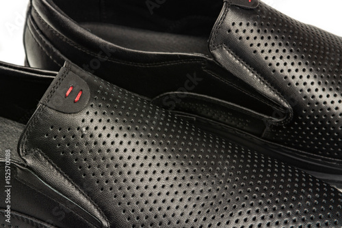 close-up details of black leather classic summer shoes with perforated trim.
