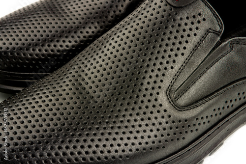 close-up details of black leather classic summer shoes with perforated trim.