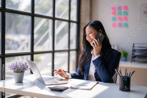 A woman is talking on her cell phone while sitting at a desk
