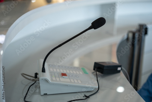 Obraz na plátně Close-up of a black gooseneck microphone with a control panel on a modern reception desk, used for public address or communication systems