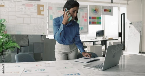 Happy young Hispanic project manager woman talking on mobile phone at large tablet with marketing financial reports, typing on laptop computer, using gadgets for work communication in office alone