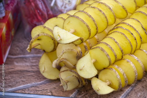 Close-up of spiral-cut tornado potatoes on skewers presents a delicious street food snack.