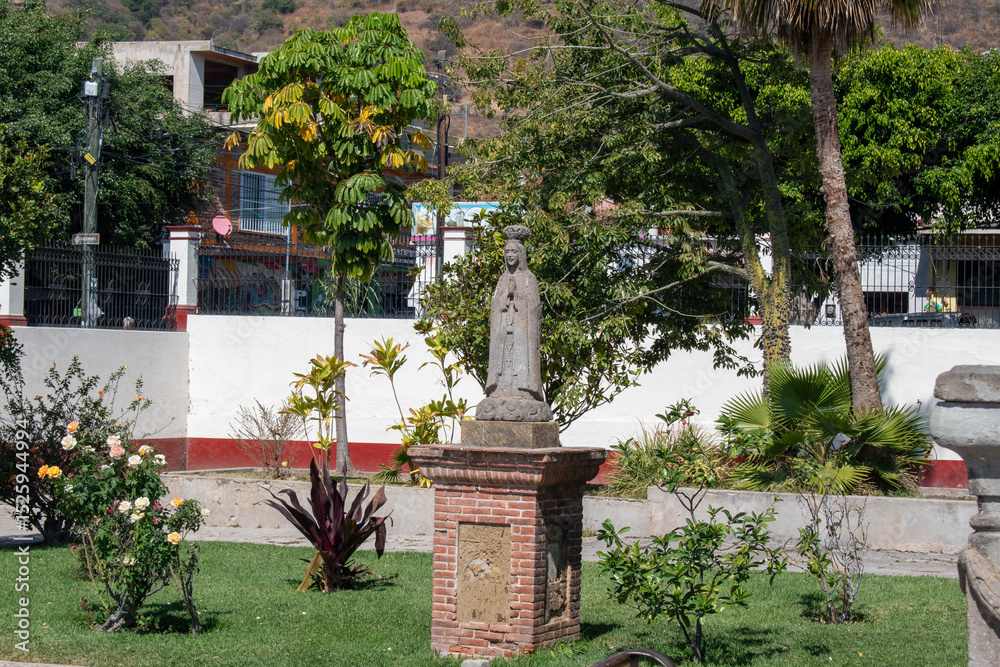 Obraz premium Ajijic, Mexico - January 26 2025: Stone statue in garden with trees and flowers in Ajijic, Jalisco, surrounded by peaceful greenery