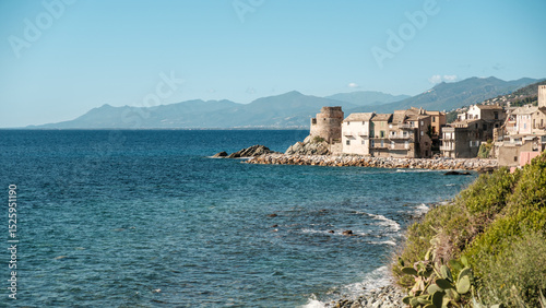 Genoese tower and the village of Erbalunga on the coast of Cap Corse on the Mediterranean island of Corsica with mountains in the distance