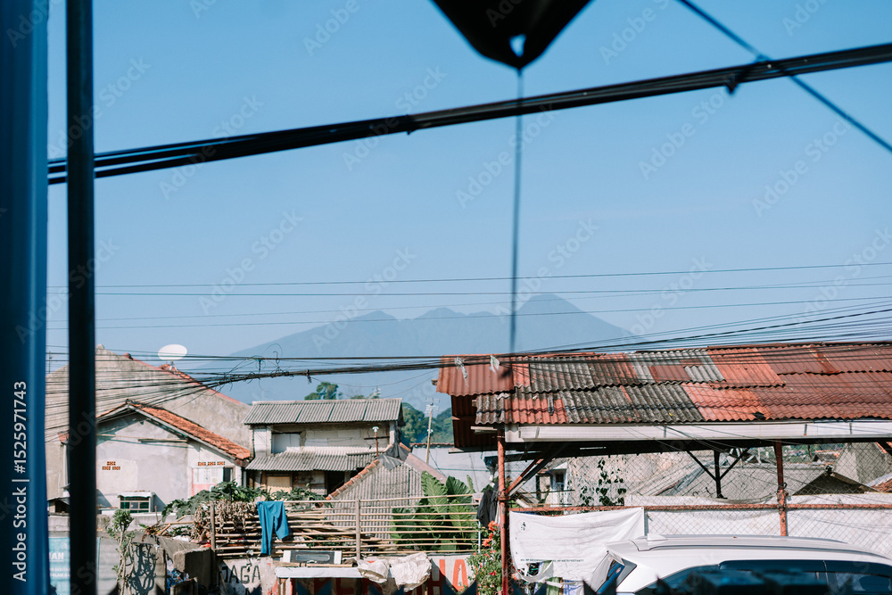 Naklejka premium Rustic rooftops against serene mountain backdrop under clear blue skies