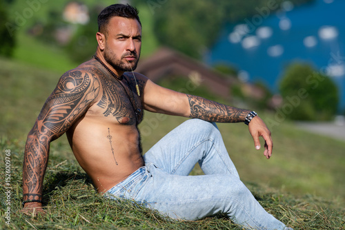 Sexy farmer man on summer field. Muscular sexy farmer rest on summer nature. Farmer posing in rural summer countryside. Shirtless sexy model relaxing on a ranch. Topless muscular guy rest on summer.