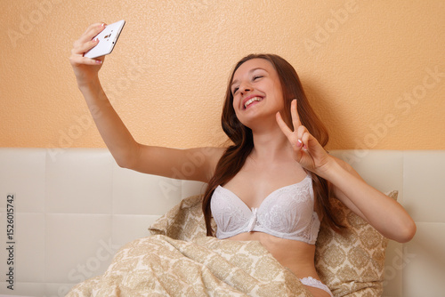 Young Woman Taking Selfie in Bed with Smartphone