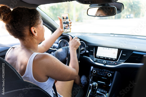 Woman driving car looking at smartphone photos and not paying attention to road