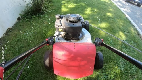 Red lawn mower is sitting on the grass