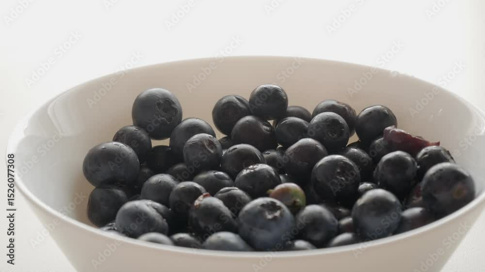 Fresh blueberries being picked from a bowl, close-up shot showing hand selecting berries