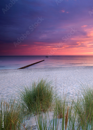 amazing colorful Sunset Over Weathered Wooden Groynes at the beach