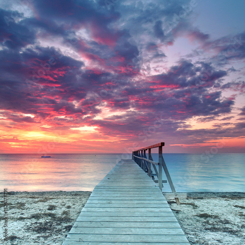 a Lonely weathered wooden pier Overlooking a Colorful Sunset by the Sea