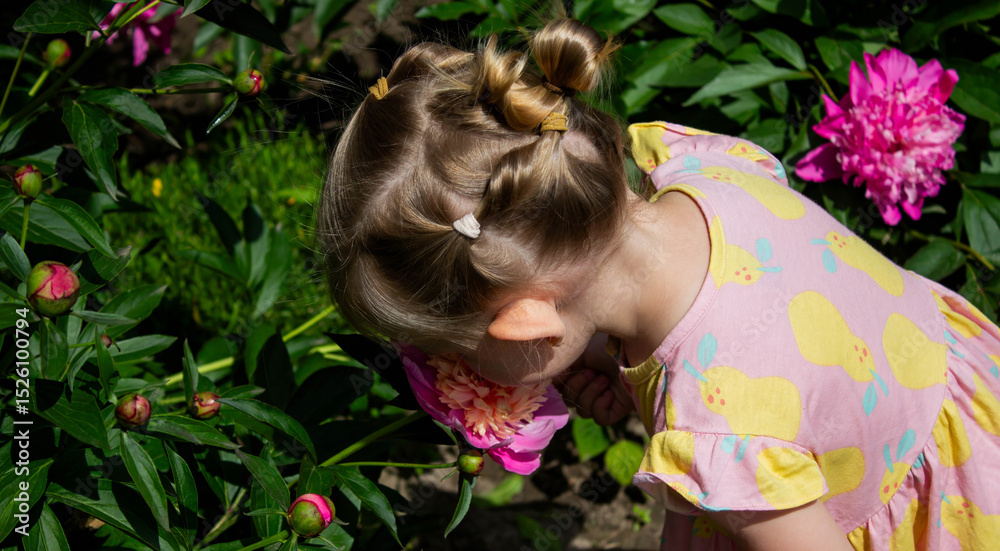 Naklejka premium little girl in the garden sniffing flowers. Selective focus