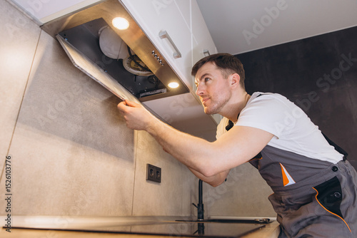 Принти на полотні Professional plumber checking extractor hood filter in kitchen