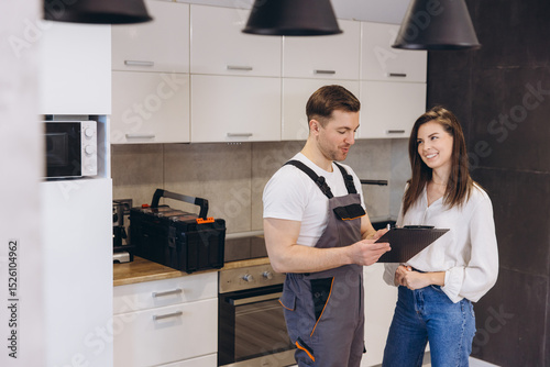 Plumber showing repair estimates to woman in kitchen