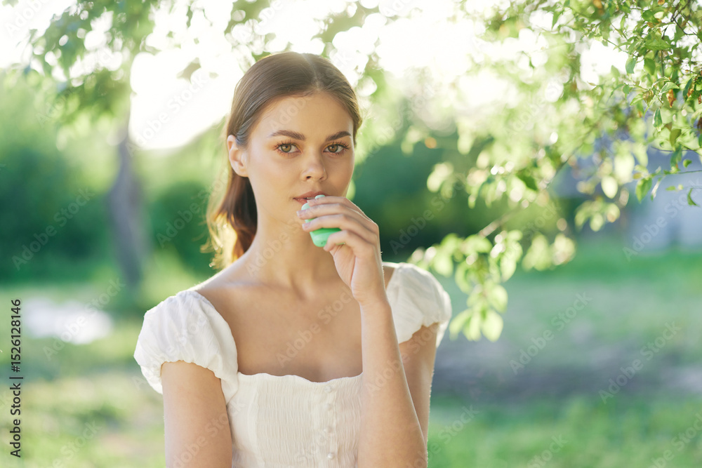 Young woman in a white dress holding a green smoothie, surrounded by greenery, conveying freshness and healthy lifestyle in a seasonal outdoor setting Young woman in a white dress holding a green smoothie, surrounded by greenery, conveying freshness and healthy lifestyle in a seasonal outdoor setting