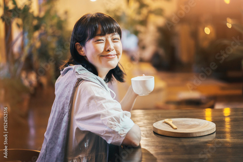 暖かい雰囲気の空間で、コーヒーを飲む若い女性