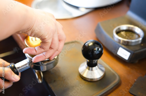 Close-up of hand Barista cafe making coffee with manual presses ground coffee using tamper at the coffee shop photo