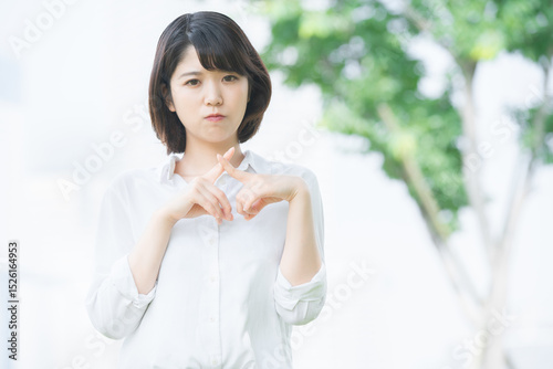 「バツ」のサインを作る若い女性