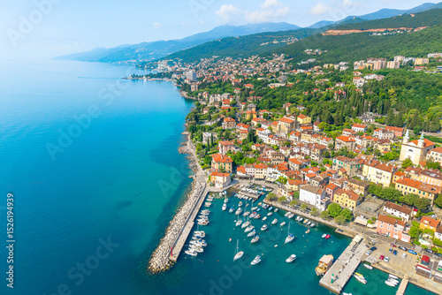 Fototapeta Naklejka Na Ścianę i Meble -  Wide aerial panorama of the picturesque Volosko town and Opatija Riviera coastline along the Adriatic Sea, featuring turquoise waters, historic buildings, and lush forested hills